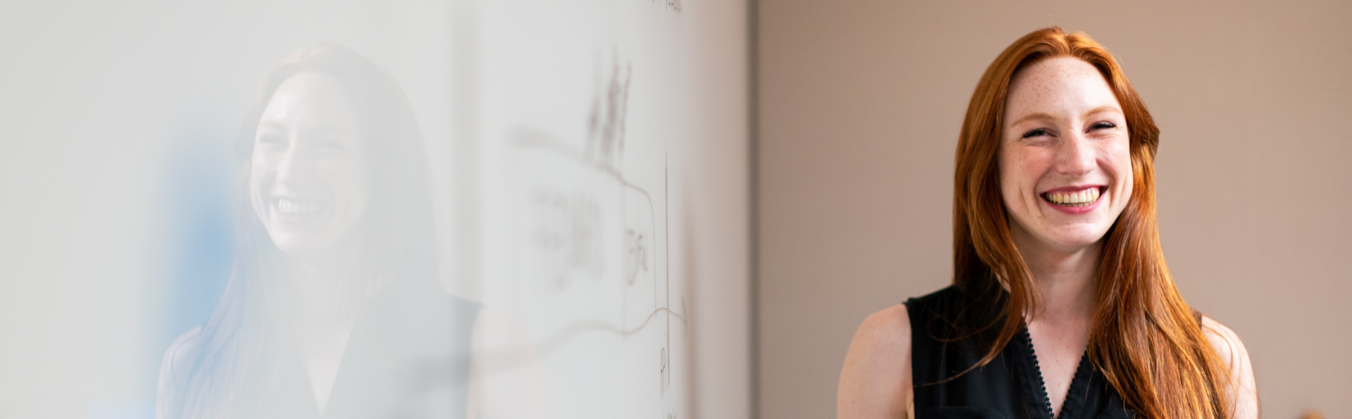 Red-haired lady standing in front of a whiteboard