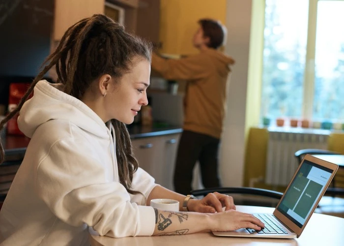 A lady working on her laptop at her kitchen table