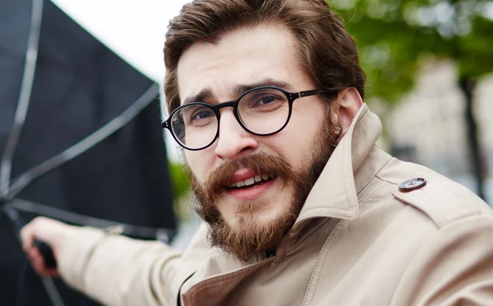 A man holds an umbrella that is being blown away