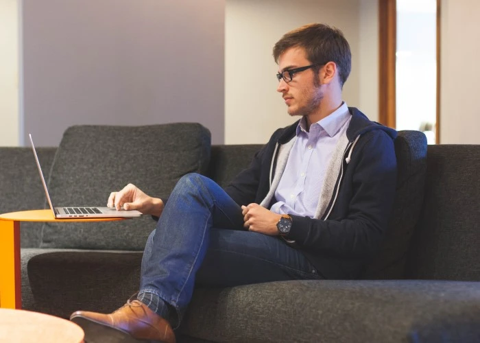 A man sitting on a sofa with his laptop