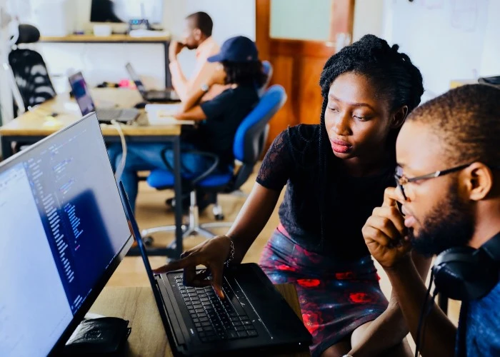 A lady showing a man something on his computer in an office environment